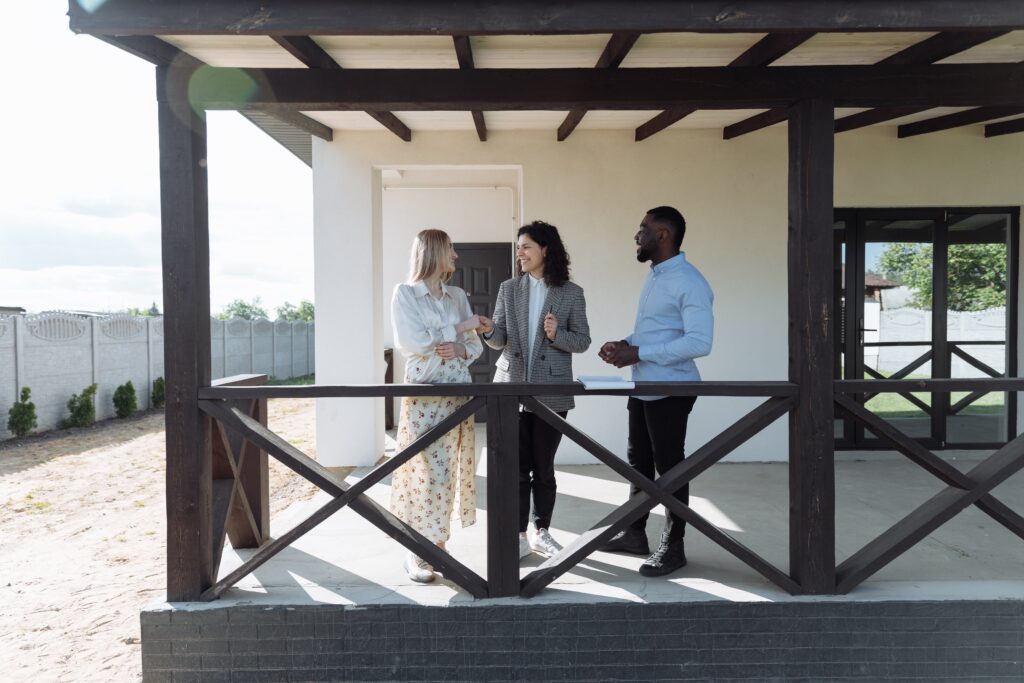 3 Menschen stehen auf Veranda und führen Besichtigung durch