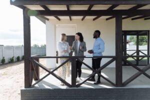 3 Menschen stehen auf Veranda und führen Besichtigung durch