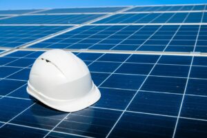 weißer Helm liegt auf einem Solarmodulfeld